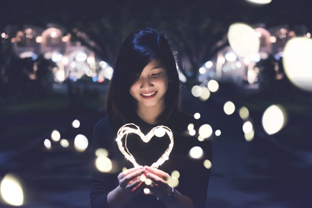 Millennial girl celebrate love holding lit-up heart