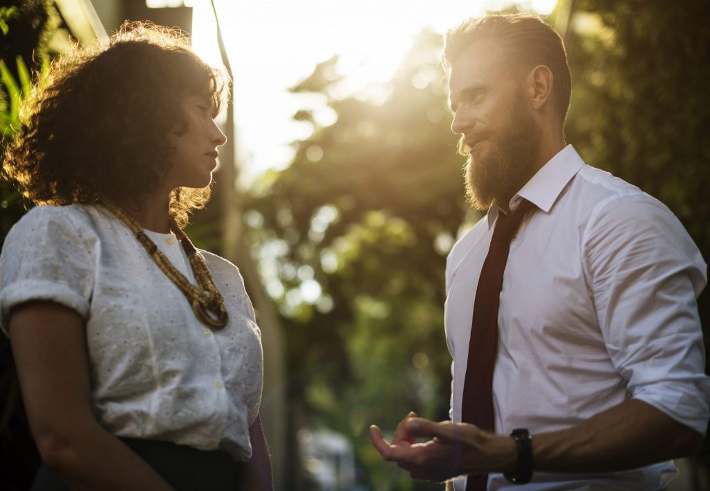 Man and Woman talking in park white shirts