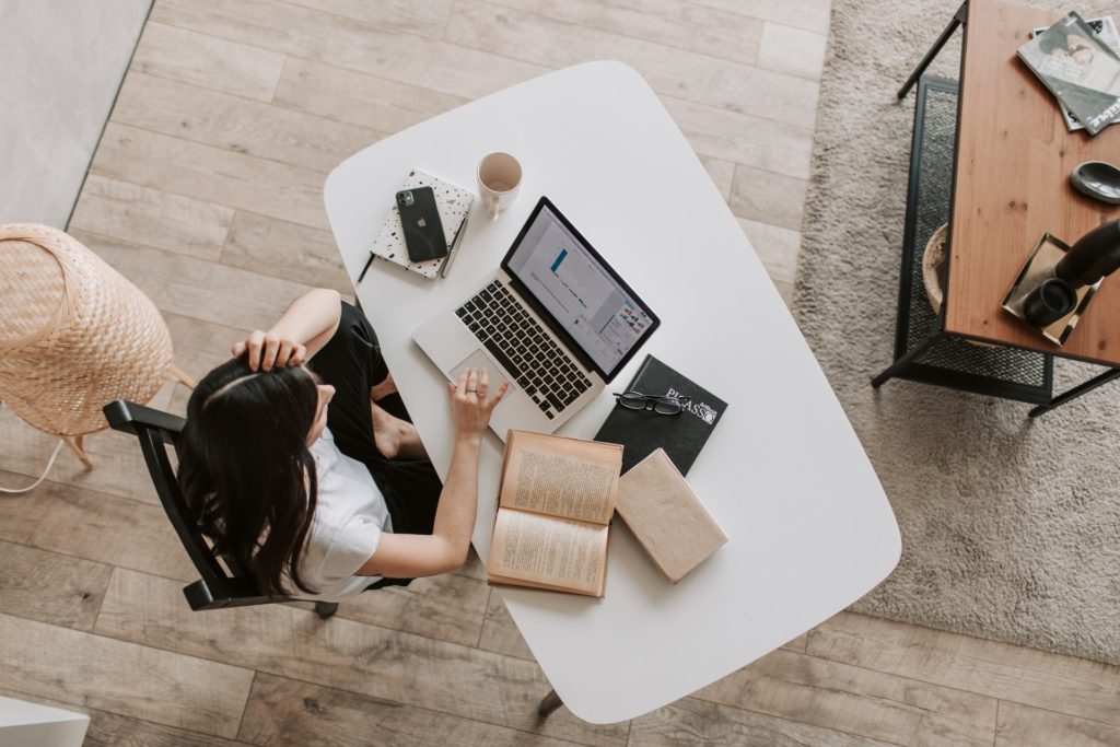 arial view of woman at desk on laptop reading email writing email newsletter